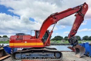 Red excavator parked on a riverside construction site in Nederland.